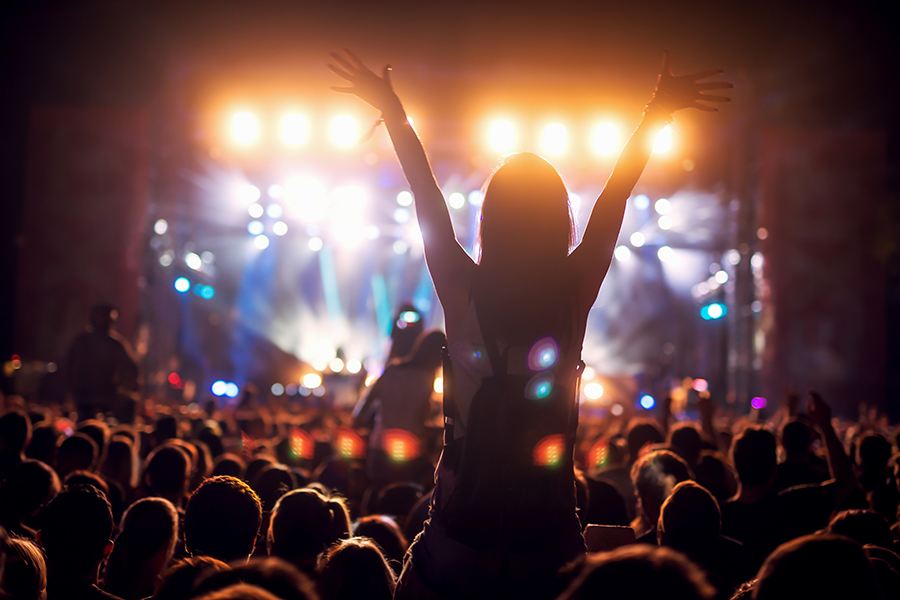 Silhouette of a girl at a concert holding her hand up and having